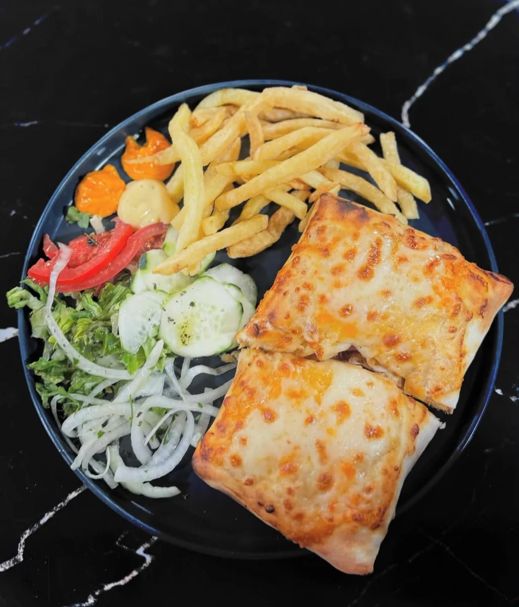 Burrito gratiné servi en assiette avec frites et salade