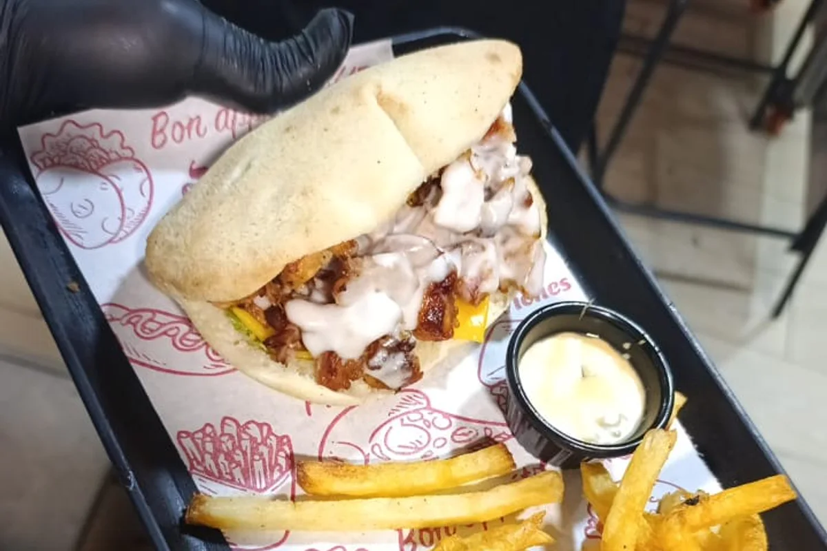 Sandwich au poulet servi avec des frites et une sauce